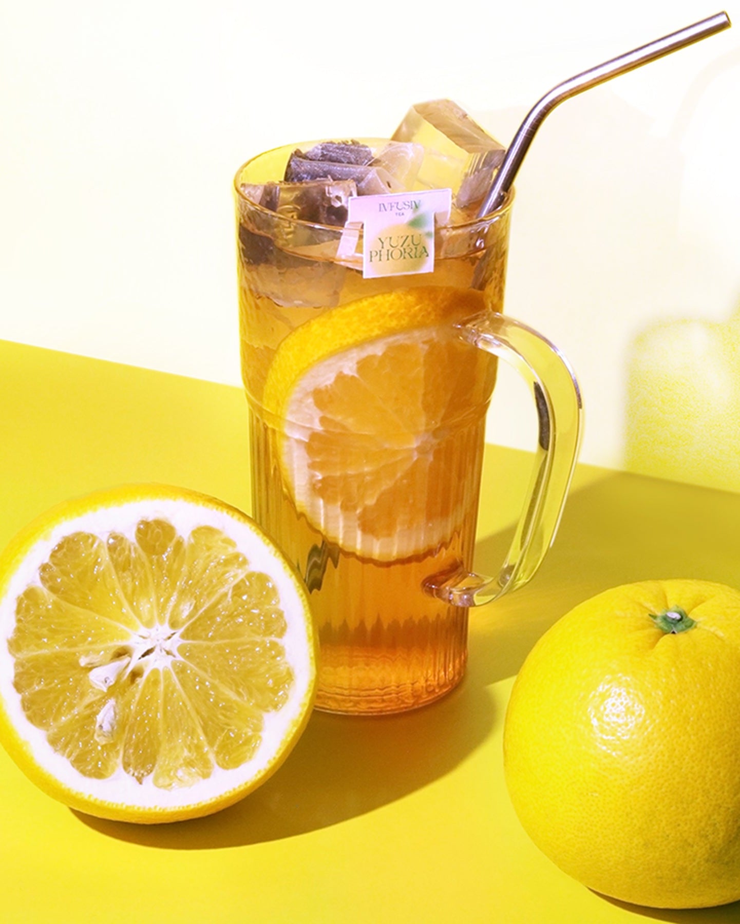 Glass of iced yuzu oolong tea with yuzu slices on a yellow surface