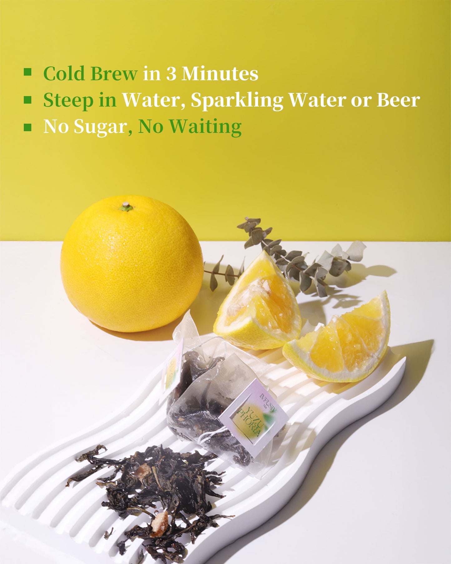 Tea bags with yuzu slices and a yuzu on a white surface with a yellow-green background