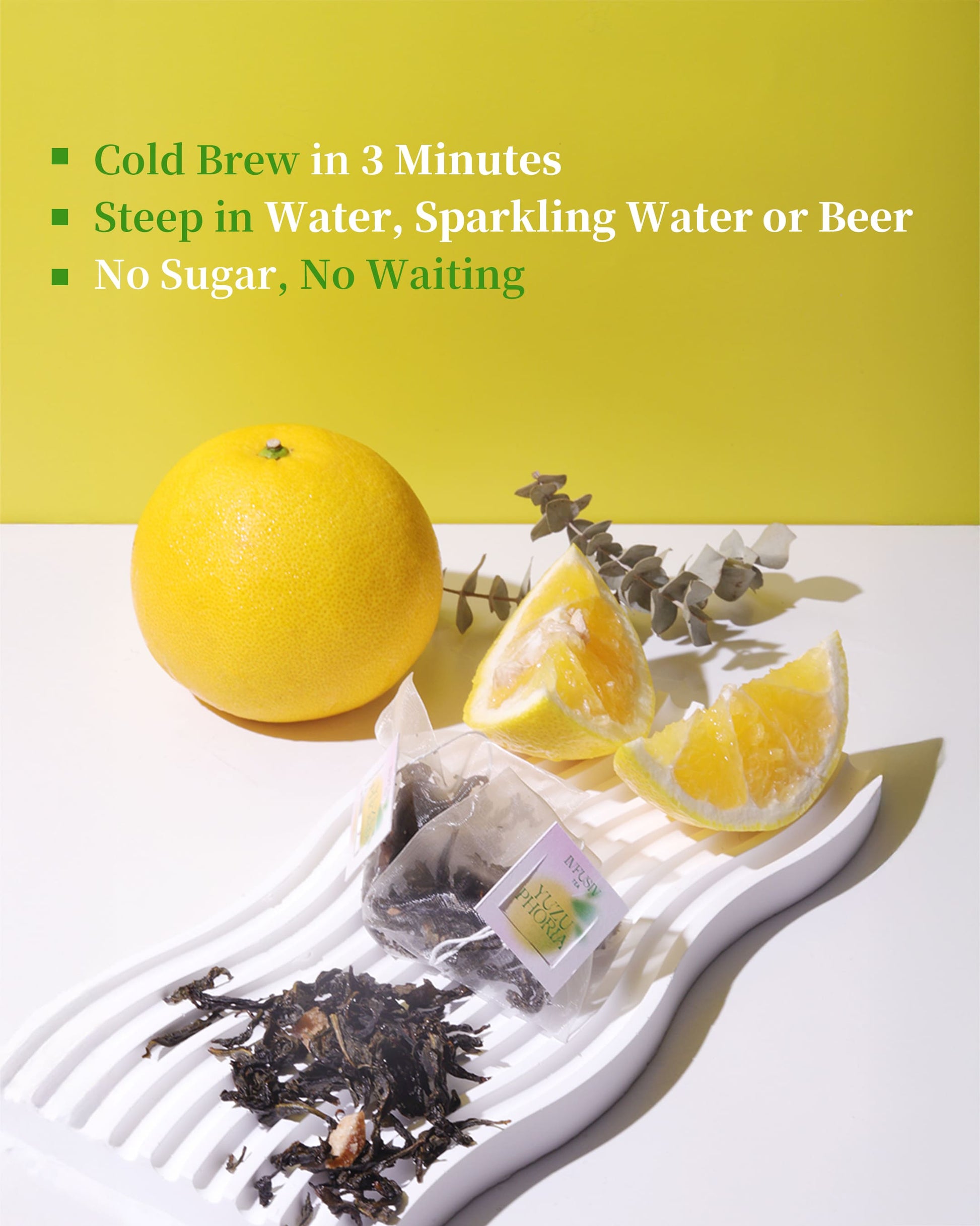 Tea bags with yuzu slices and a yuzu on a white surface with a yellow-green background